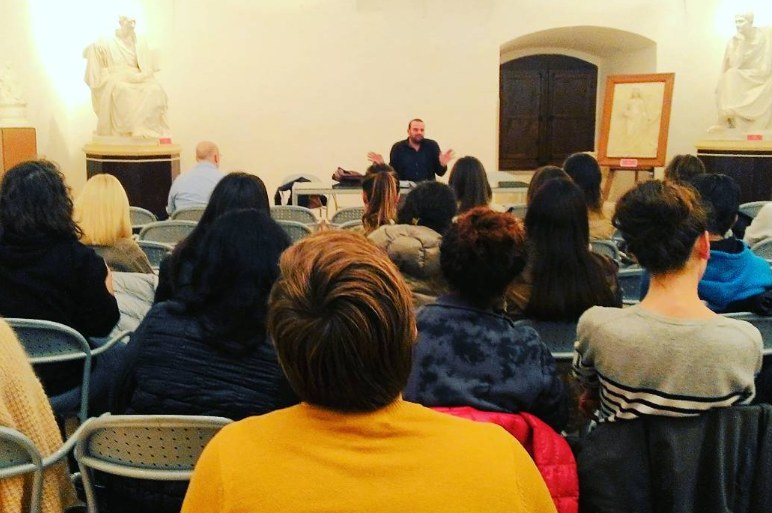 Un incontro di Formebrevi: il pubblico seduto ascolta il relatore in una sala con statue